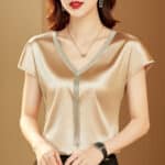 Blouse courte en satin couleur beige avec ornements dorés.