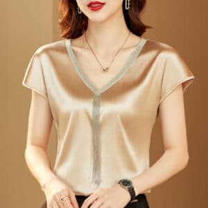 Blouse courte en satin couleur beige avec ornements dorés.