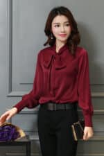Blouse satinée rouge foncé à manches longues avec un nœud.