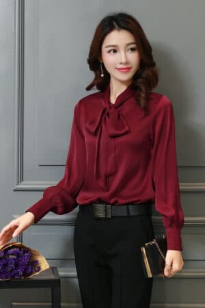 Blouse satinée rouge foncé à manches longues avec un nœud.