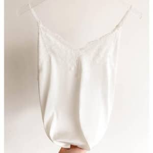 Débardeur en satin à fines bretelles orné de dentelle blanche.
